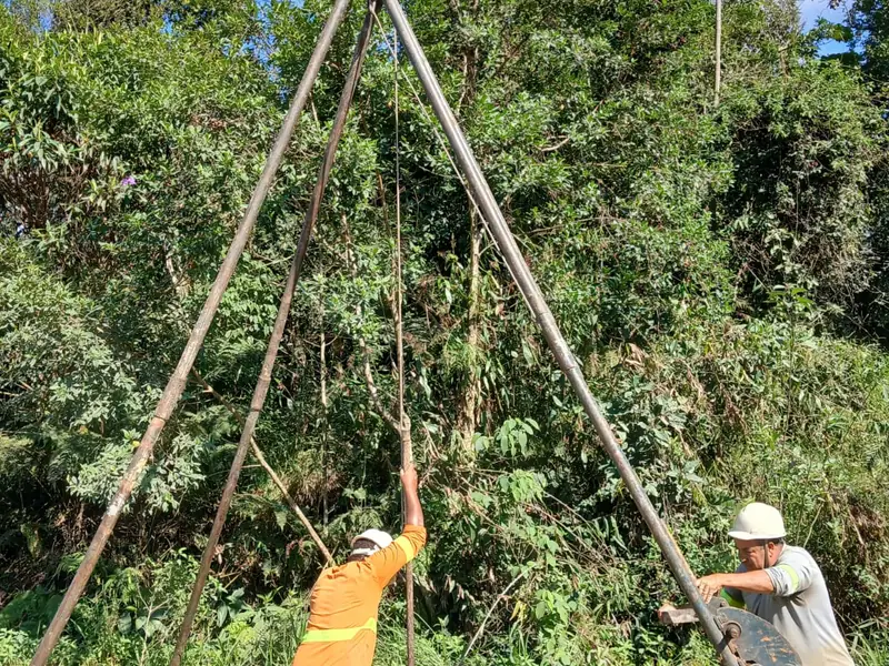 Equipe de campo do Grupo NEV operando o tripé de sondagem em área de mata